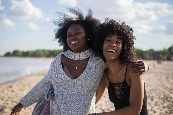 Two African American women smiling on the beach.